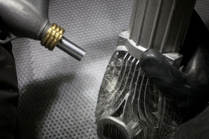 Close-up of the bead blasting process on a custom machined part to create a uniform matte finish.