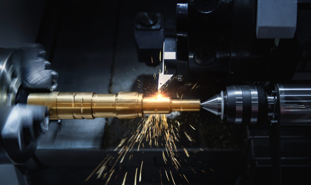 Close-up of CNC lathe turning golden metal shaft, metal sparks generated during hard alloy tool cutting cylindrical precision parts