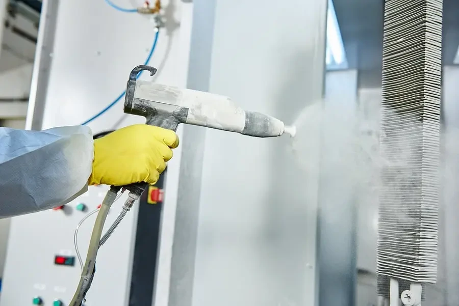 Technician applying industrial powder coating to a custom aluminum heatsink for durable surface protection.