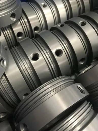 Stack of durable precision CNC machined components treated with a Type III hard coat anodizing finish for wear resistance.