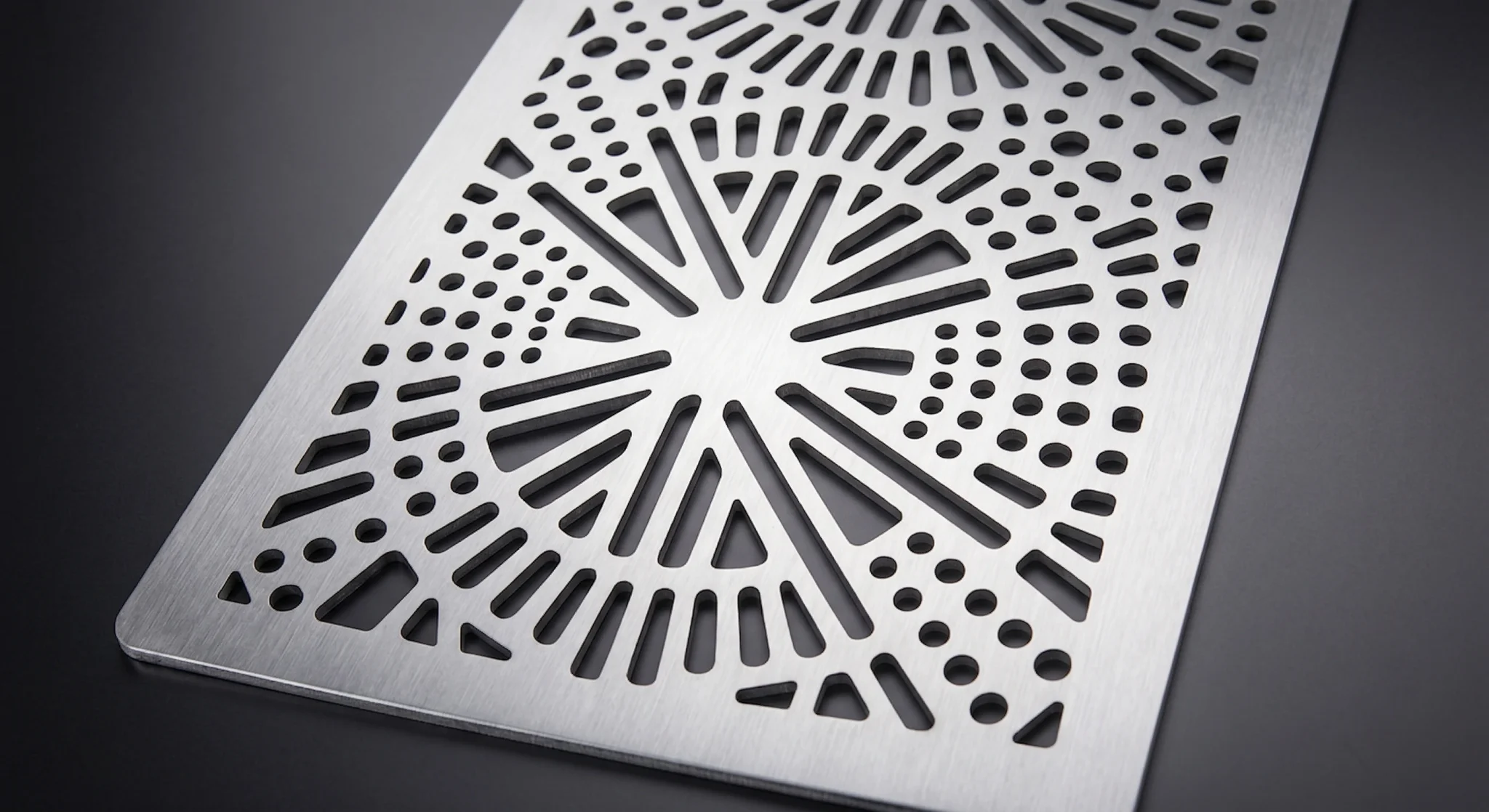 Intricate decorative hole pattern laser-cut into aluminum panel feature with crisp and distinct edges