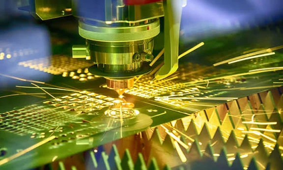 A detailed close-up shot of a precision CNC laser cutting head processing a complex pattern into a metal sheet with a bright cascade of sparks.